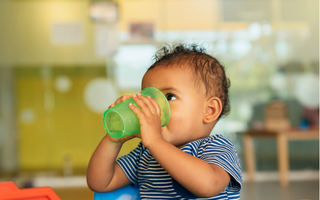 a baby drinking water out of a sippy cup