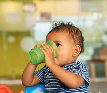 a baby drinking water out of a sippy cup