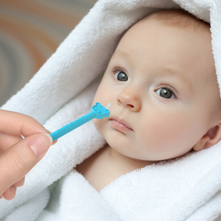 Mom using oogiebear booger picker tool on a newborn baby